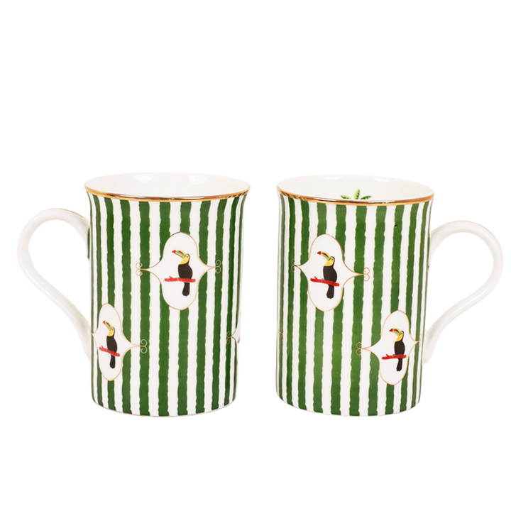 Two Toucan Tango mugs side by side in green and white stripes with gold trim, each featuring a toucan bird motif in an ornate white medallion